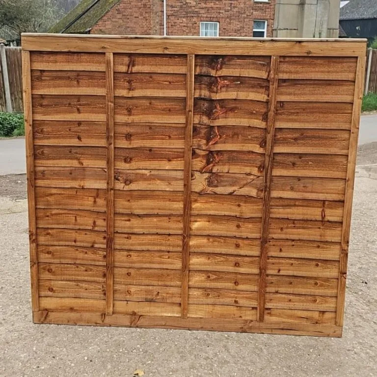 Wooden overlap fence panel with a rich brown stain displayed upright outdoors.